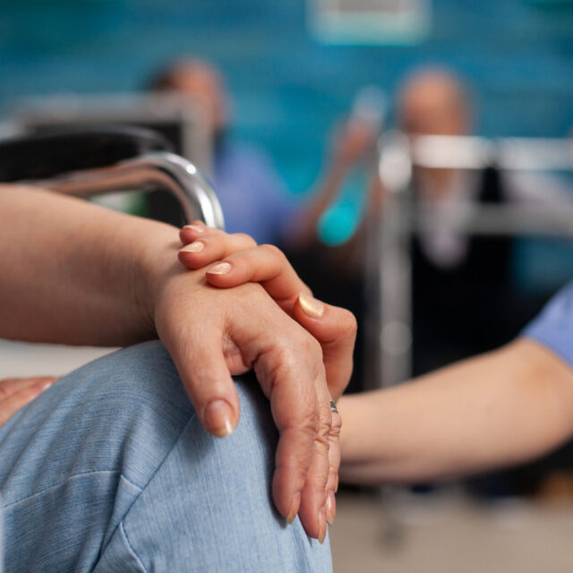 social assistant worker consoling handicapped pensioner patient touching hands